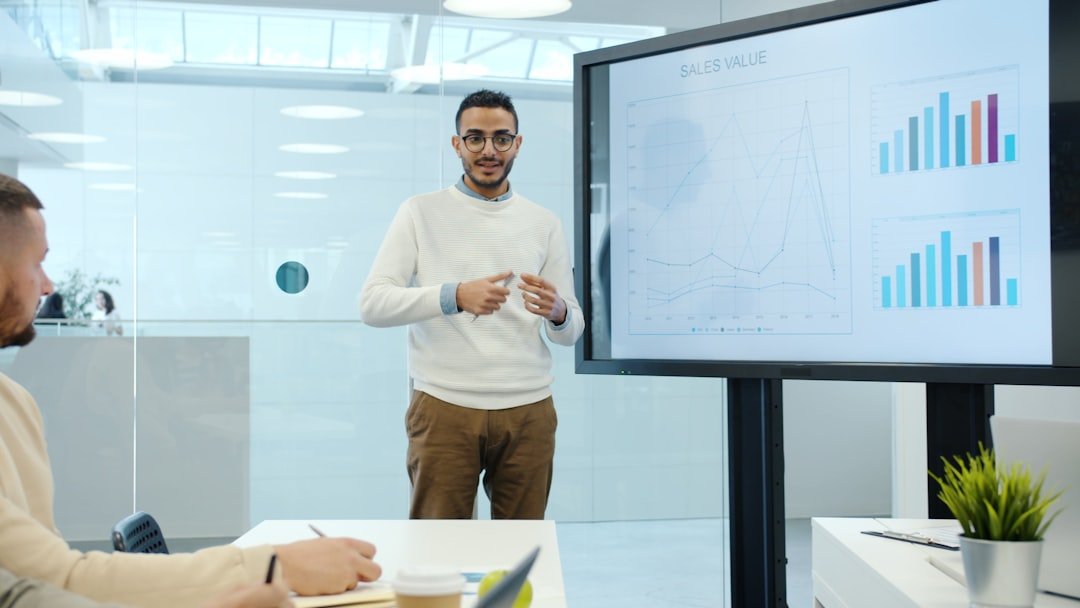Arab man discussing marketing research with group of people in office using interactive board for presentation talking and gesturing indoors.